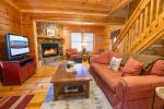 Living Room Features a Flat Screen TV, Wood Burning Fireplace, & Access to Covered Screened in Deck